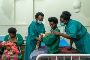 Dr. Angelique Charlie Karambizi teaching a new mother how to hold her baby against her chest.