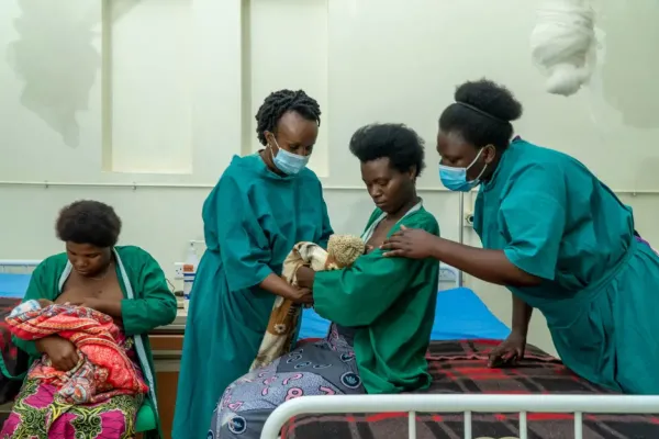 Dr. Angelique Charlie Karambizi teaching a new mother how to hold her baby against her chest.