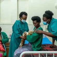 Dr. Angelique Charlie Karambizi teaching a new mother how to hold her baby against her chest.
